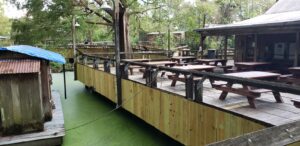 A wooden deck with picnic tables and benches.