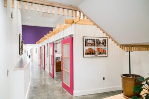 A hallway with pink doors and white walls.