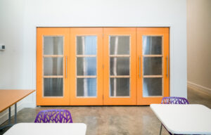 A room with four orange doors and glass windows.
