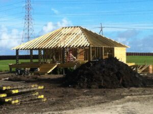 A house with straw roof and pile of dirt.