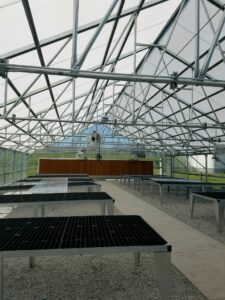 A large greenhouse with tables and benches in it.